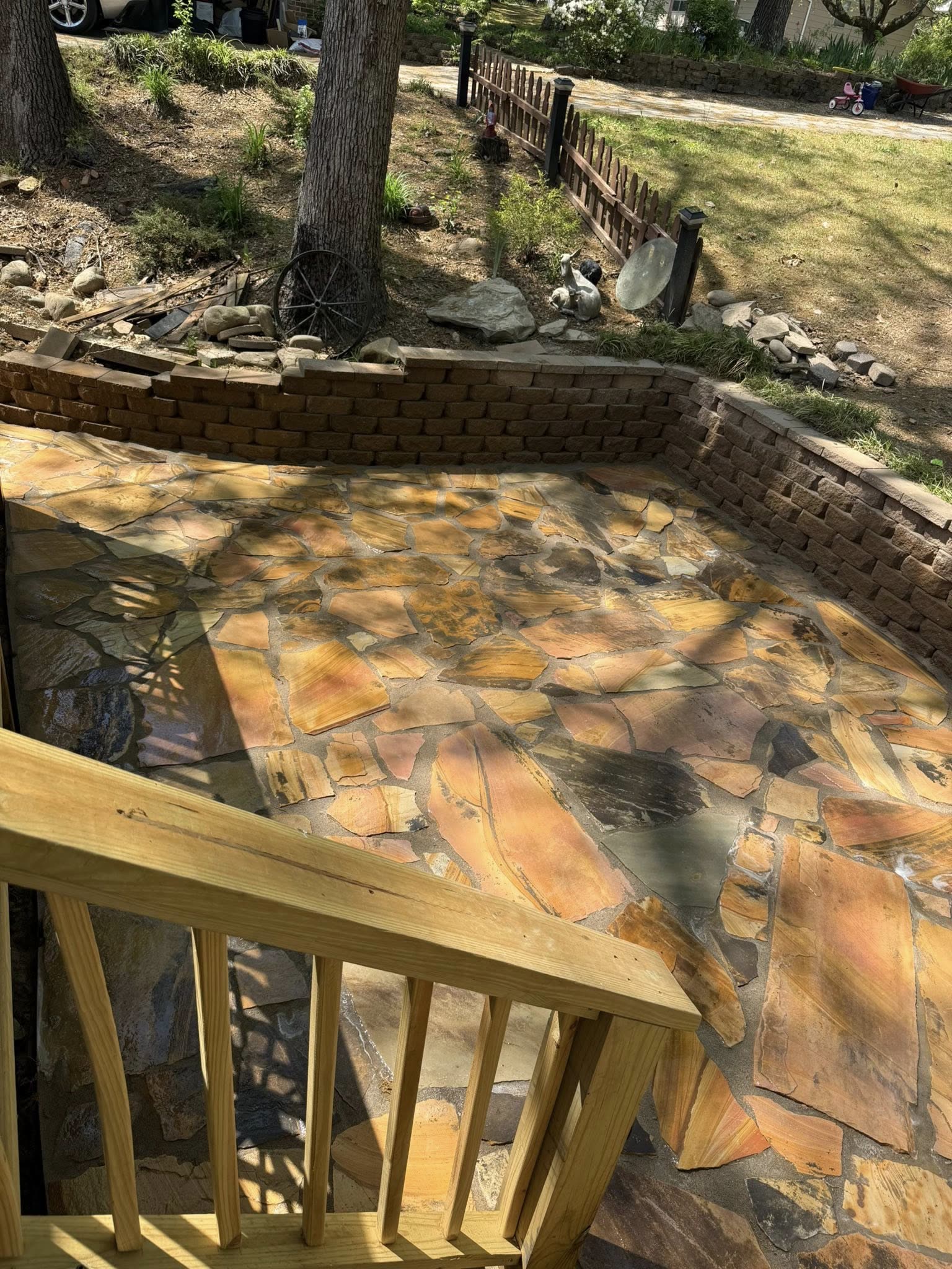 Flagstone patio set below a curved block retaining wall, seen from the deck stairs, Chattanooga TN area